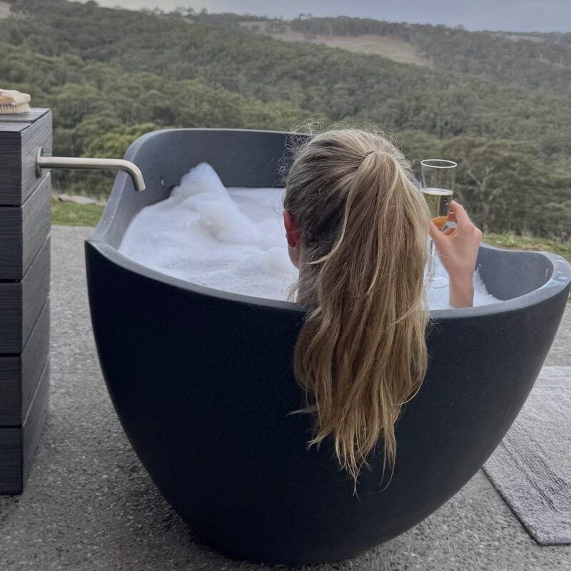 Luxurious outdoor bubble bath overlooking native Australian bush.